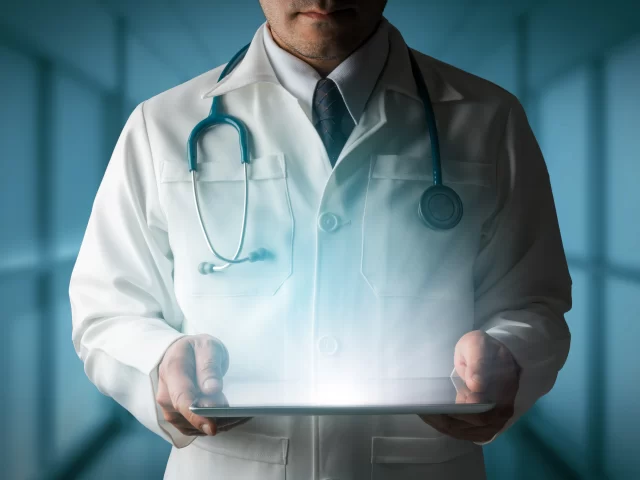Doctor in a white coat holding a digital tablet, representing TheKnowHow in Abu Dhabi, a medical field intermediary.